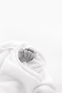 A black and white image of a baby's feet wrapped in a white fabric.
