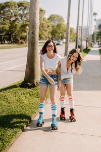 two women on roller skates skating down sidewalk