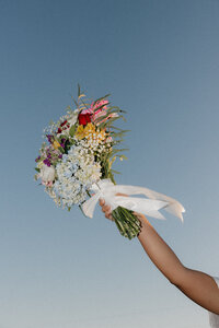 bridal bouquet held up against the blue sky