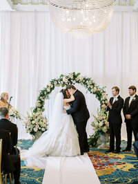 Elegant indoor wedding ceremony at The Jefferson Hotel in Washington DC with floral arch and crystal chandeliers, photographed by a luxury DC wedding photographer