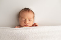 Sleeping baby boy with hands above blanket at NEWBORN PHOTOGRAPHY COLUMBIA MD session