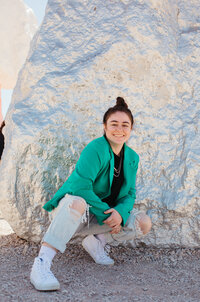 Girl in orange hoodie smiling while holding a cookie to her eye.