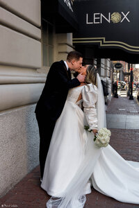 man kissing woman in front of historic boston hotel