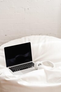 Laptop y audífonos sobre la cama.