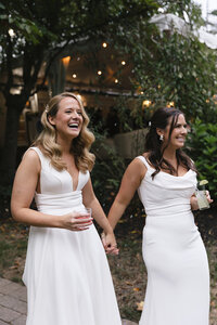 Two brides sitting on the backseat of a golfcart