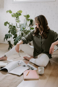 Website copywriter Erika Fitzgerald sitting on the floor surrounded by books and papers while brainstorming website copy ideas