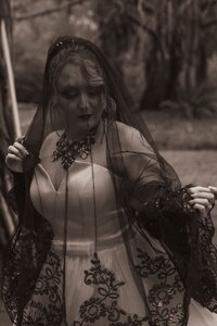 Bride in strapless gown with dark veil and dramatic makeup in outdoor portrait