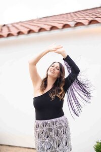 Dynamic brand portrait capturing joyful movement in flowing black dress against light background during creative photoshoot