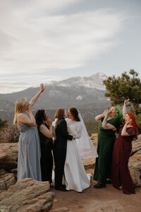 A wedding party standing next to a newlywed as they adjust their suit