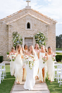 Bride and bridesmaids in pink dresses smiling at each other