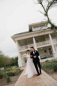 Bride and groom walking arm in arm down a path with a large house in the background