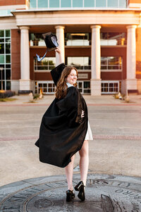 Senior holding cap and celebrating outside the MTSU library