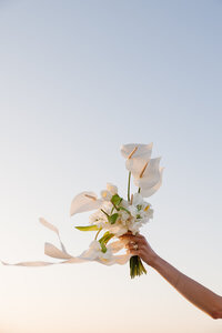 A hand waving a boquet of flowers in the air