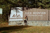 Kelsie sits on a sign for Duck Mountain Provincial park in Manitoba. Taken on film.