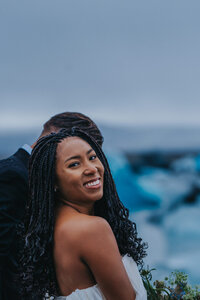 Woman smiles and looks over her shoulder while holding hands with her new husband