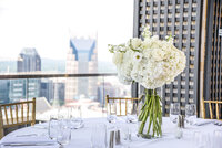 Hydrangea and Anemone centerpiece for rooftop reception in downtown Nashville with Batman building in background of skyline