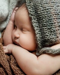 A baby sleeping in a knitted hat.