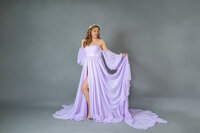 A pregnant mom in a purple dress posing in a Gainesville studio.