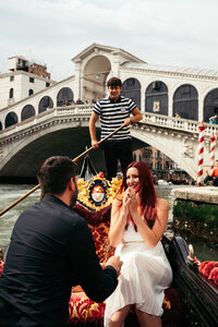 A Japanese couple sits on the steps by a Canal in Venice while taking photos for their honeymoon