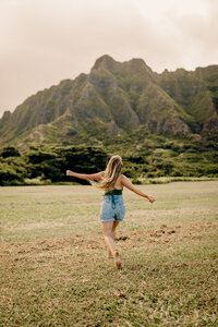 woman running through the field with mountains around