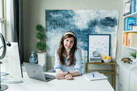 Virtual assistant client wearing magenta shirt sitting at a desk with an Apple computer