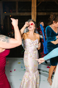 Bride at reception dancing and singing while wearing pink sunglasses