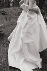 Close-up of a bride’s gown with a large back bow, photographed in the woods by a Washington wedding photographer.