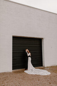 bride and groom posing in front of black door