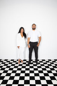A man and woman posing on a checkered floor at an Austin photo studio.
