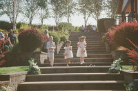 Flower girls and boy coming down the steps, representing film captured by Eugene wedding photographer Among the Oaks. 