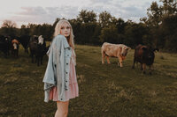 Senior girl looking away in field  with cattle in Bangor, Wisconsin