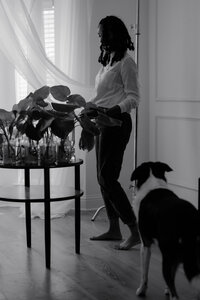 A black-and-white lifestyle image featuring Nerissa James in a home setting, surrounded by natural light and engaging with her environment. This photo highlights her passion for capturing authentic moments in her unique and sophisticated photography style within the DFW area.