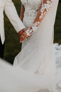 Detailed photo capturing the intimate moment as the bride and groom hold hands.