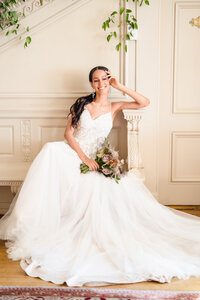 A bride reclines in her wedding dress and smiles