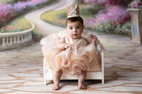 Baby girl celebrating half birthday wearing a crown and couture gown near Floresville 