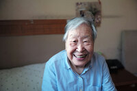 Older lady sitting on the bed smiling