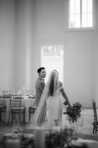 Black and white image of bride and groom walking inside their wedding reception