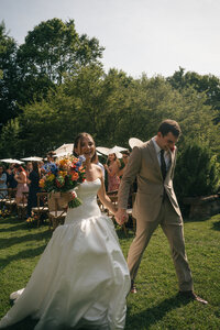 black and white overlay of bride being assisted by someone in a suit, white wedding dress train being carried during wedding photography session