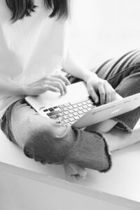 Escribiendo en laptop con pies cruzados.