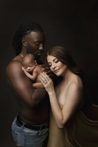 mom and dad cuddling baby in newborn session in studio