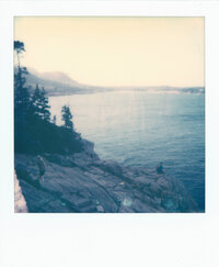 Polaroid photo of a quiet rocky coastline and distant ocean horizon — a personal analog landscape captured by the film wedding photographer team at Castillo Holliday Photo + Film, known for Super 8 wedding films and analog wedding storytelling.