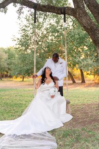 A bride and groom joyfully seated on a swing, surrounded by a picturesque outdoor setting, celebrating their love.