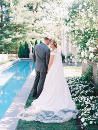 bride and groom walk beside a pool