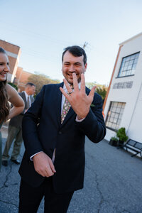 A groom showing off a wedding ring
