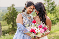 Bride embraces bridesmaid at the Shiraz Garden wedding venue in Bastrop, Texas.
