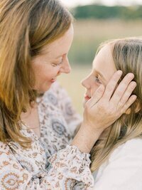 Mother and daughter looking at each other while mom puts her hand on daughters cheek.