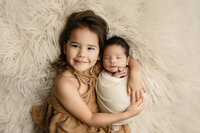 Siblings laying together smiling in Fort Collins studio