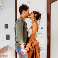 Family Photographer, a couple  holds hands and kisses in their home