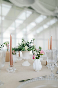 wedding table layout with flowers in vases and pink candles
