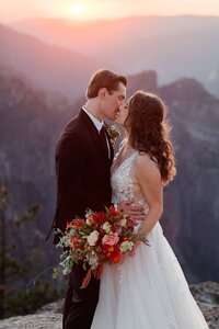 A bride and groom kiss at sunset while atop Taft Point at Yosemite National Park. 